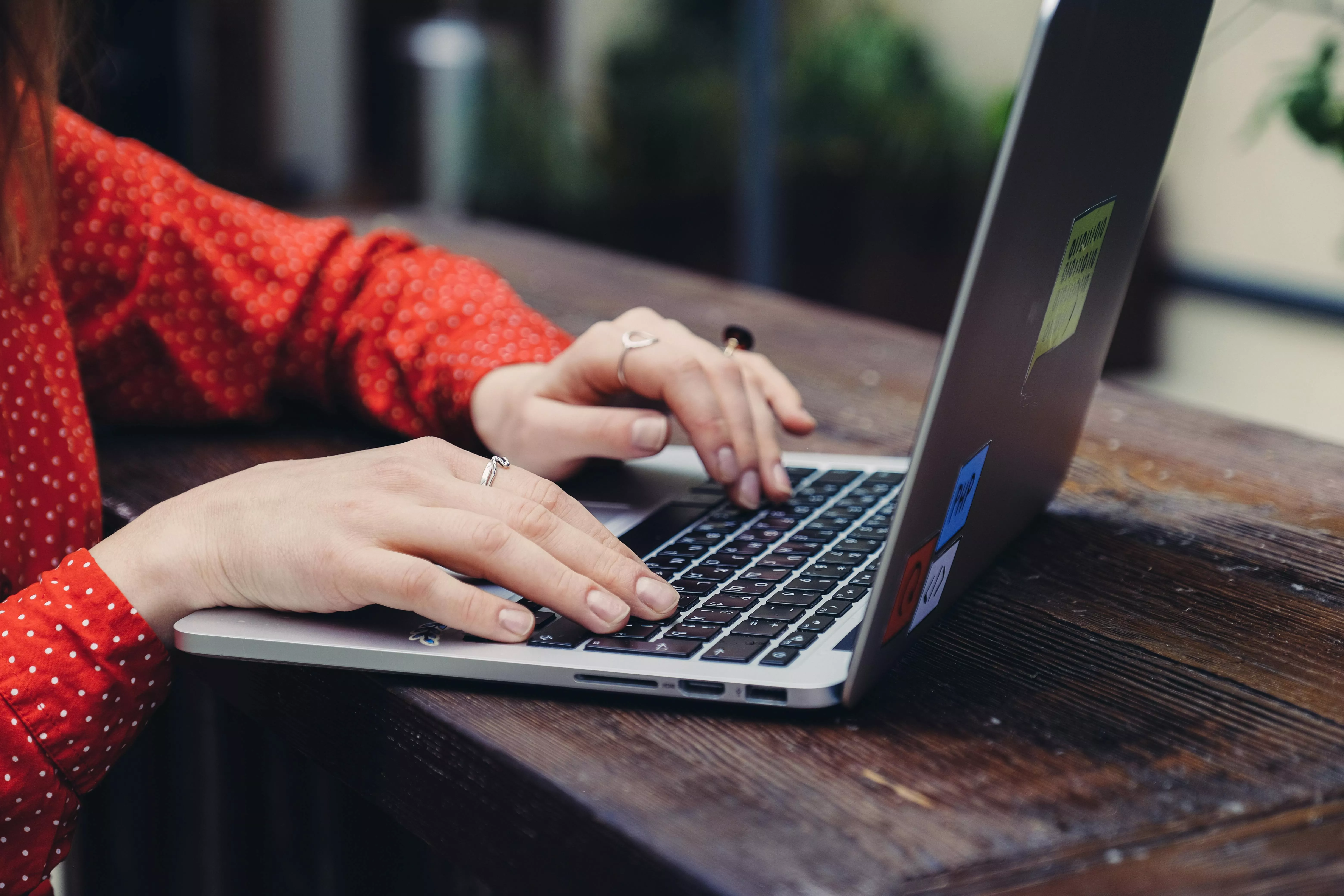 A photo of the hands of a woman typing on a laptop computer.