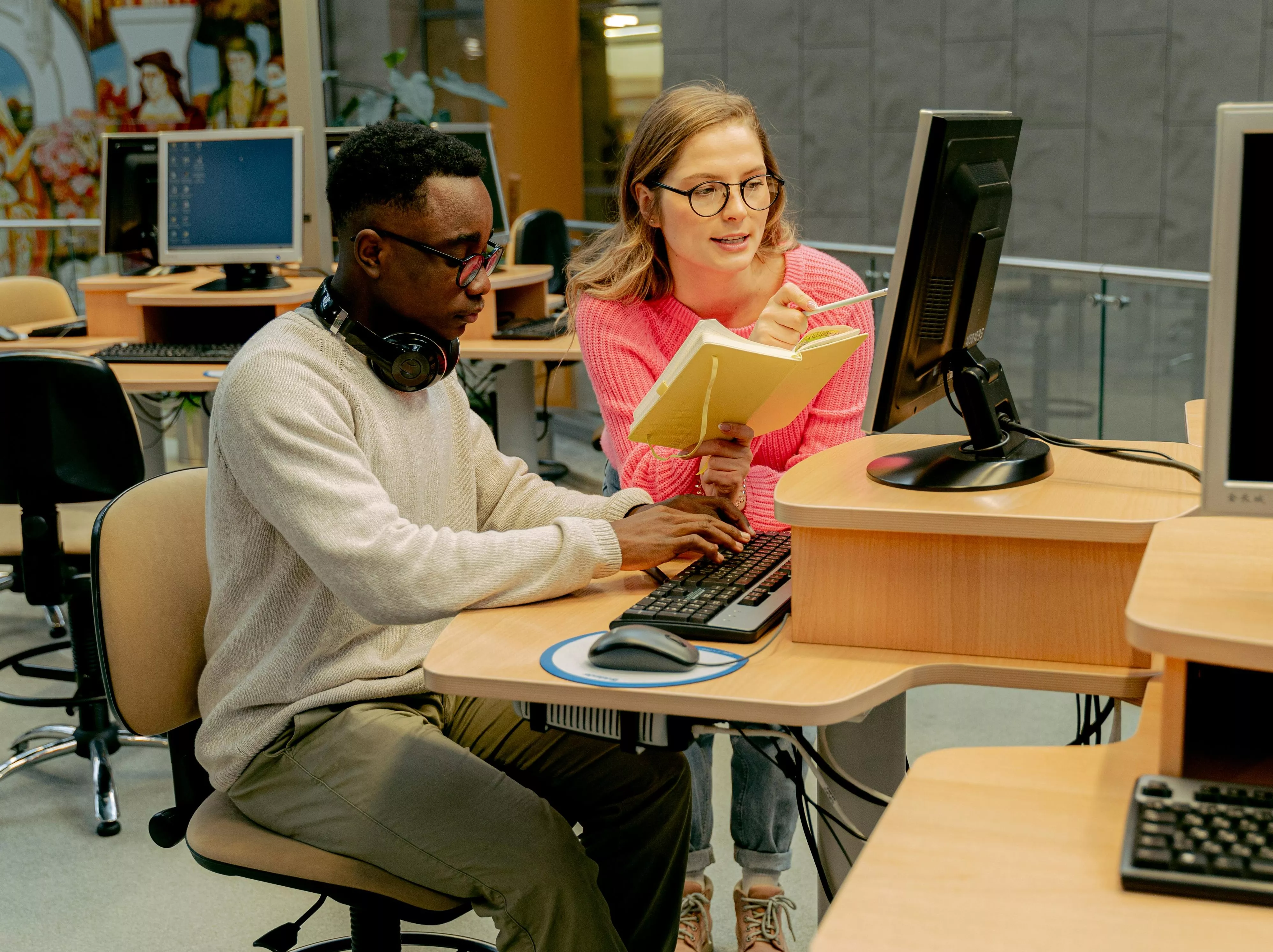 Photo of two adults in a computer lab using a computer together.