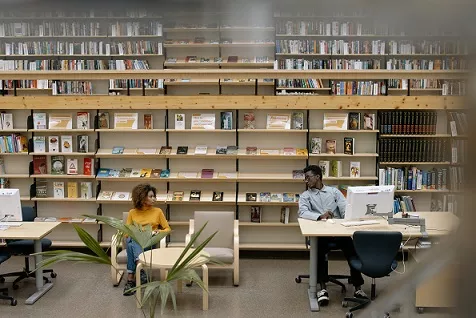 Photo of two people sitting in a library.